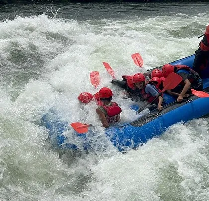 Splashing right into the action. A raft hits a wave head-on, drenching the smiling participants during a thrilling run in Dandeli.