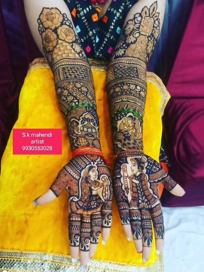 This design features the couple in a romantic pose. The arms are decorated with elephants and floral patterns, creating a full bridal look.
