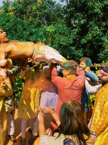 The groom is tossed in the air by his friends during a wild and colorful Holi-themed celebration.