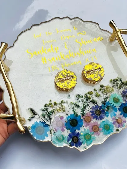 A beautiful design featuring a garden of pressed flowers at the base of the tray. The multi-colored flowers create a stunning contrast with the white resin and yellow ring holders.