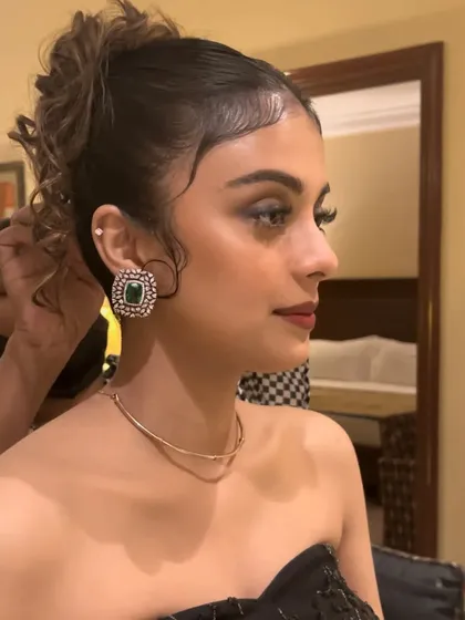 A side profile showing the intricate details of the hairstyle and makeup. The soft curls framing her face and the precisely blended smokey eye create a truly stunning look for the reception party.