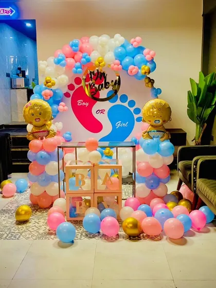 This full view shows a complete gender reveal party setup in a restaurant or hall. The backdrop, balloon pillars, and scattered balloons on the floor create an immersive and exciting atmosphere for the big reveal.