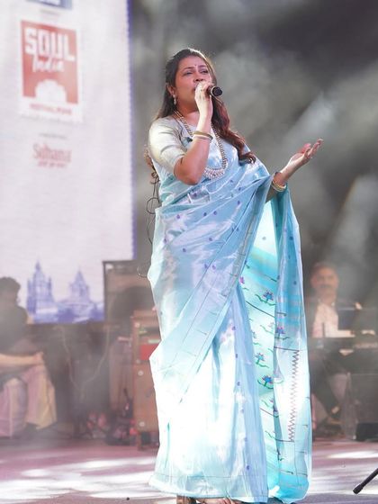 The full stage view, where the pastel saree stands out beautifully against the dramatic lighting.