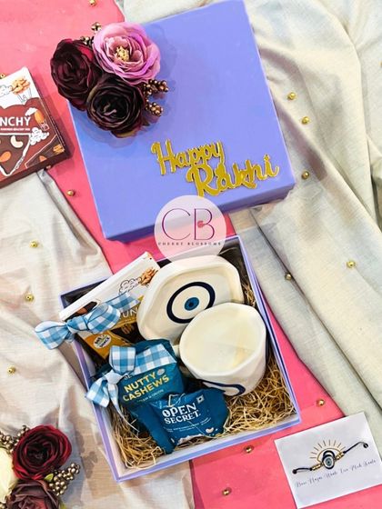 Another look at our popular evil eye themed Rakshabandhan hamper. The lavender box is beautifully decorated and filled with a matching mug, trinket tray, healthy snacks, and a rakhi.