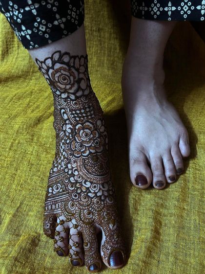 A stunning bridal leg henna design with full coverage. The intricate floral and paisley patterns wrap around the foot beautifully, ensuring a complete and traditional bridal look.