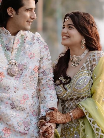 Another beautiful shot of the couple holding hands, showing the harmony between their outfits and the bride's mehndi.