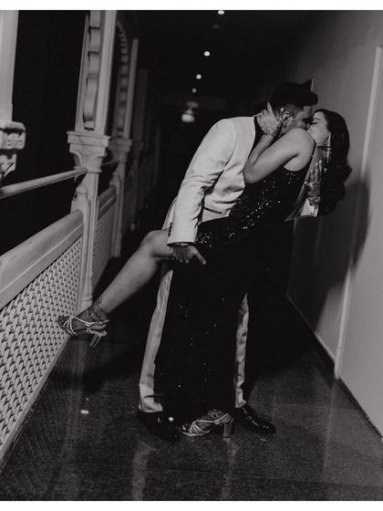 A passionate, cinematic kiss in a dimly lit corridor. This black and white shot feels like a still from a classic movie.