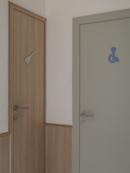 Simple, clear, and playful signage on the doors. A small graphic icon for a spatula indicates a utility room, while a universal accessibility symbol is used for another, ensuring the design is intuitive for all.