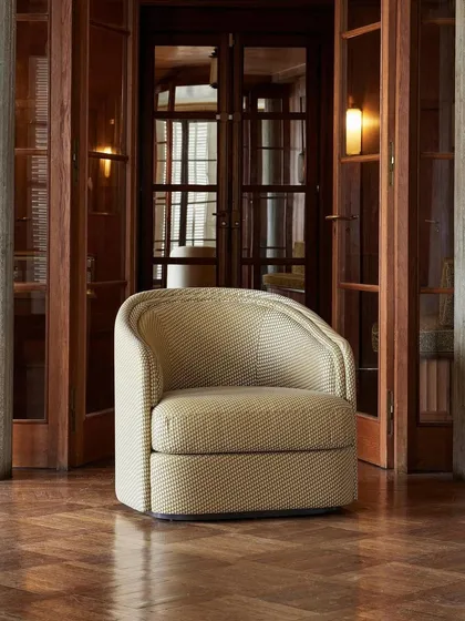 Set within a classic interior, the 'Boromeo' armchair stands as a testament to timeless design. The textured fabric and elegant silhouette make it a versatile piece that complements both traditional and modern environments.