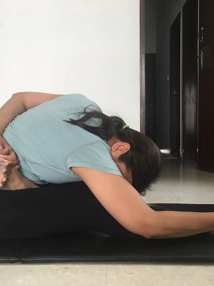 A student practicing Ardha Baddha Padmottanasana. The pressure of the heel on the abdomen in this pose helps alleviate gastric problems and constipation.