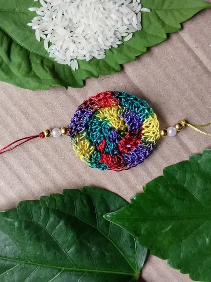 A beautiful multicolored rakhi with pearl and gold bead details.