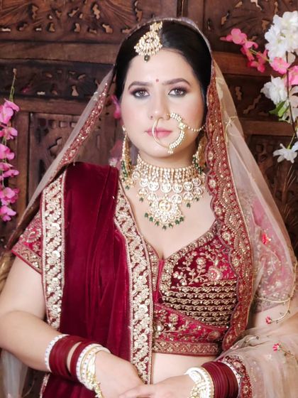 A classic bridal portrait in a maroon velvet lehenga. The bride is wearing a beautiful Pachi Kundan choker with a matching nath and maang tikka.