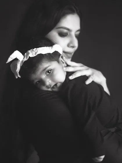 A baby peeking over her mother's shoulder, looking right at the camera. This soulful black and white portrait is both beautiful and engaging.