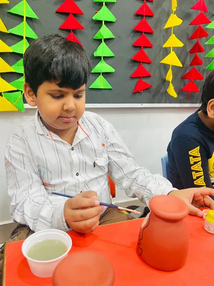 A moment of focus as a student carefully paints his terracotta diya holder.