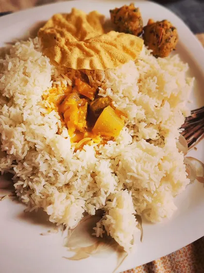 A simple and wholesome South Indian thali. This meal features fluffy rice with tangy Sambar, accompanied by crispy papad and savory bonda, making for a light yet satisfying lunch.
