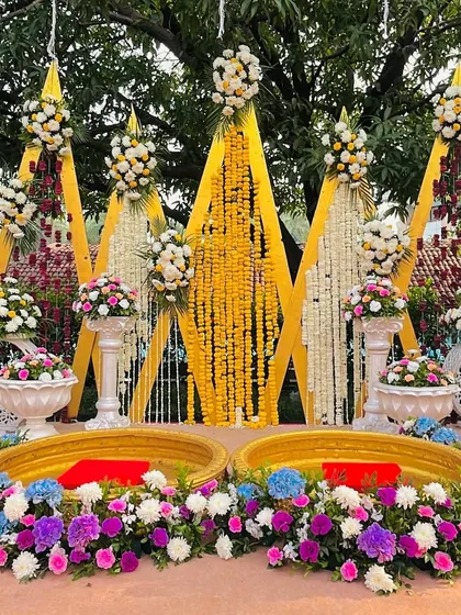 The main seating for the Haldi ceremony, beautifully decorated with yellow and white flowers and colorful floral arrangements.