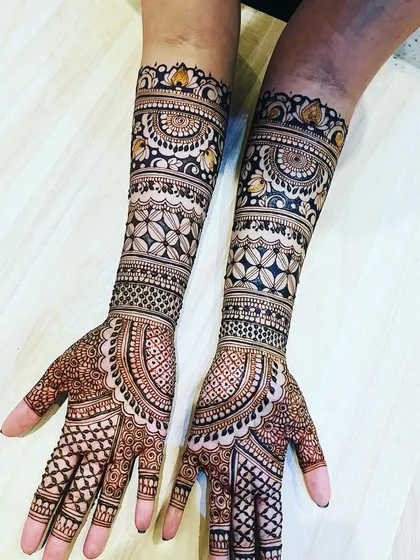 A beautiful example of a full coverage bridal mehendi. The design uses bands of geometric and floral patterns to create a rich, textured look that extends to the elbows.