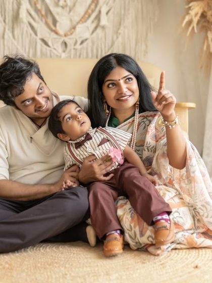 A family sits together, with the mother pointing up at something to entertain her son. This candid interaction adds a lovely, natural feel to their family portrait.