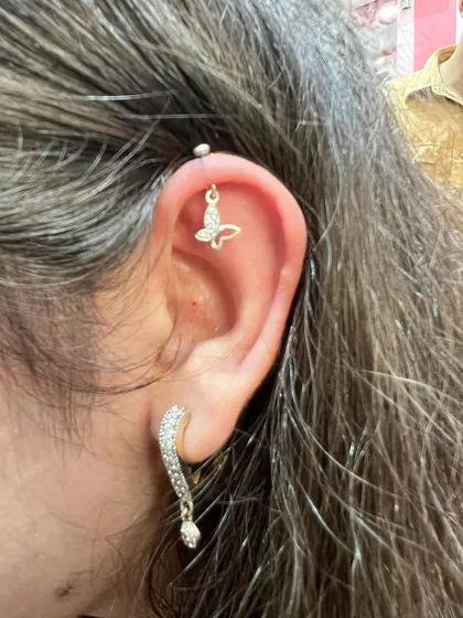 A delicate butterfly hanging from the helix, paired with a sparkling drop earring on the lobe for a light and airy look.