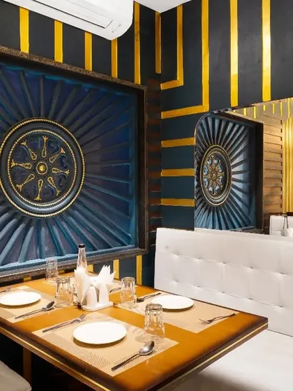 The interior of The Rogan, a restaurant in Kolkata, featuring bold black and gold striped walls and custom blue art panels. The design is dramatic, luxurious, and creates a memorable dining experience.