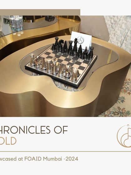 A close-up of the fluid, organically shaped coffee table from our FOAID exhibition, showcasing its brushed gold finish and the custom chess set that completes the look.
