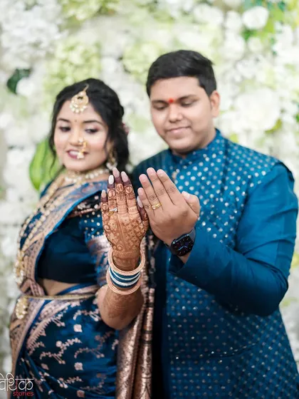 A lovely moment from a Maharashtrian wedding where the couple displays their hands, showing the bride's beautiful mehndi design and their wedding rings. It's a simple, happy photograph that documents an important tradition.