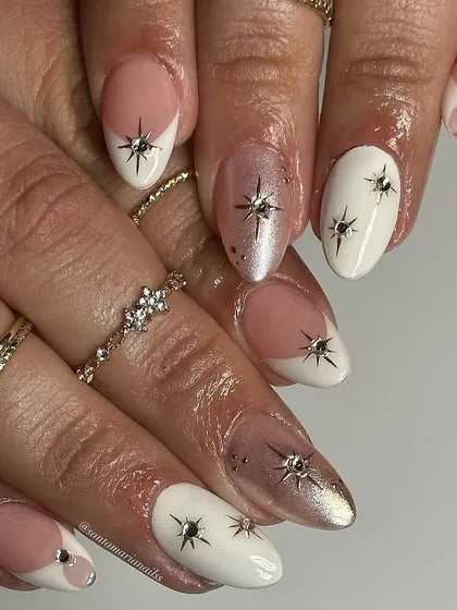 A celestial-inspired design with white and sheer nails, adorned with hand-painted starbursts and tiny rhinestones for a magical touch.