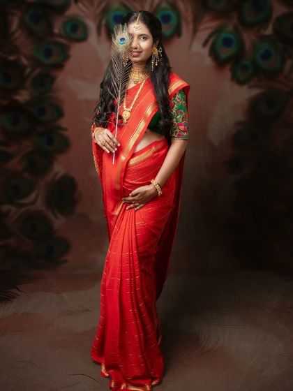 Unveiling the beauty of motherhood. This stunning maternity shot in a red saree with a peacock feather tells a story of love, grace, and anticipation.