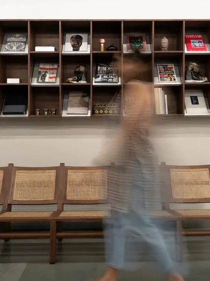 A detail of the showroom's waiting area, featuring a cane bench and a curated library of design books. The space is designed to be both welcoming and inspiring.