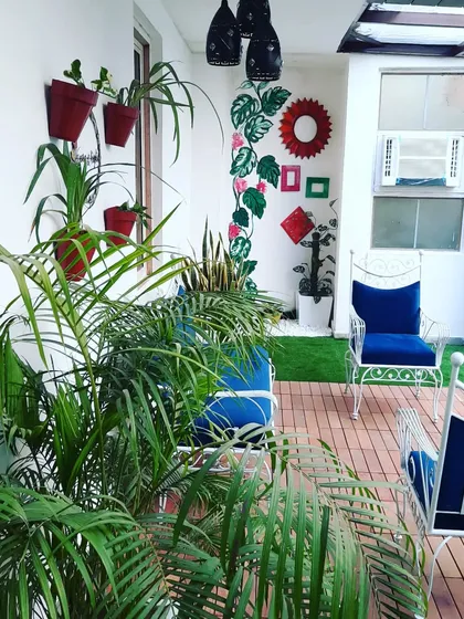 A cozy sitting area on a small patio, filled with plants and featuring comfortable iron chairs.