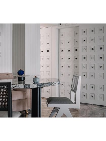 A detail of the dining nook, showing the mix of black and white chairs against the marble table.