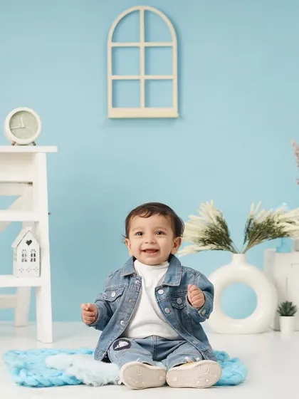 A wide-angle shot of a baby boy's first birthday setup, showing the full blue-themed set with charming props like a teddy bear and miniature furniture.