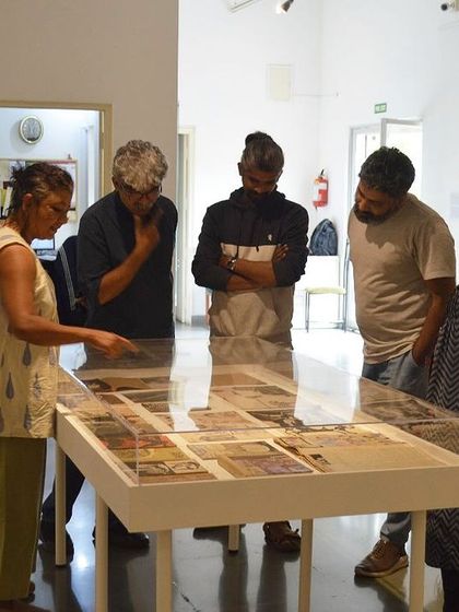 Artists and visitors gathered around the vitrine displaying journals and book covers by Gulammohammed Sheikh.