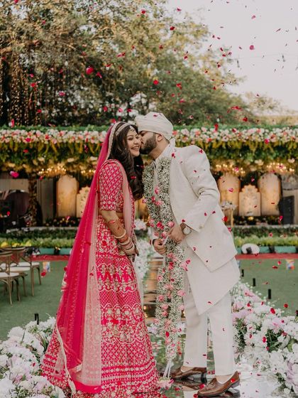 A fairytale moment with a shower of rose petals. The bride's soft makeup and pink lehenga create a romantic and dreamy scene.