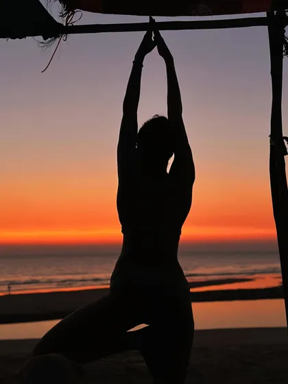 In this silhouette, the focus is on the form of the Tree Pose against the vibrant colors of a Goa sunset. It's a moment of dancing with the shadows, finding stability and grace as the day ends.
