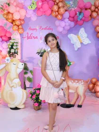 The birthday girl poses at her enchanting woodland-themed party. The large, cute animal props create a storybook setting.