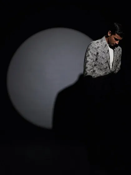 Using dramatic lighting, this shot puts the focus squarely on the patterned suit jacket, creating a sense of mystery and high fashion intrigue.