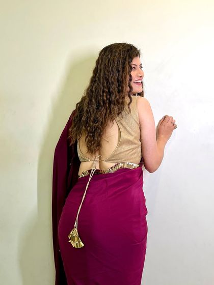 A playful shot of Savaniee in a simple yet elegant magenta saree. The focus is on her beautiful, natural curls and the stylish backless blouse.