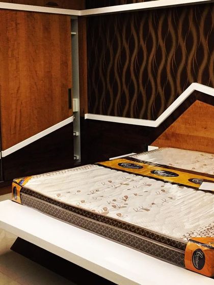 This bedroom design uses bold geometric lines on the headboard and wardrobe, creating a dynamic and modern look. The contrast between the dark wood and white accents is sharp and contemporary.