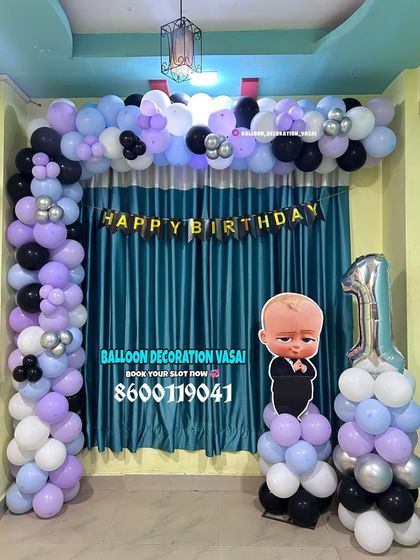 A Boss Baby theme for a first birthday. This simple balloon arch in purple, black, and white is paired with a character cutout and a number '1' foil balloon.