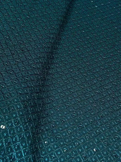 A dark teal green Chikankari fabric. The intricate embroidery and sparse sequin work give it a refined look suitable for formal ethnic wear.