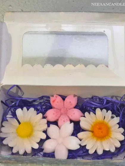 A beautiful gift box of our handmade flower candles. This set includes two daisy candles and two cherry blossom candles, nestled in purple shredded paper.