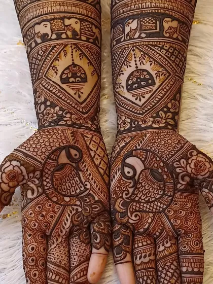A very symmetrical and clean bridal design with bold peacocks on the palms and jhumki motifs on the arms.