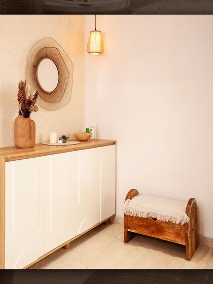 The foyer of the Japandi villa, featuring a simple white console with curved details and a minimalist wooden bench.
