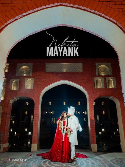 A stunning wide shot of the couple framed within the grand archway of the Noor Mahal Palace, capturing the scale and royalty of their wedding entrance.