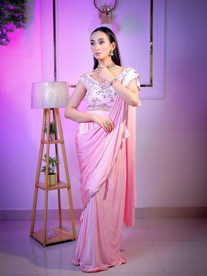 A full-length shot showcasing the modern draped saree, with studio props adding context to the scene.