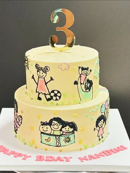 The full view of the two-tier doodle cake for Nandini's 3rd birthday. Each little drawing represents a special memory or hobby, creating a cake that's as meaningful as it is delicious.