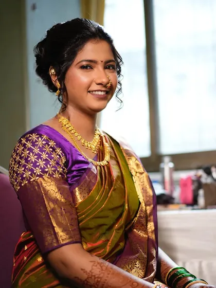 A classic portrait of a Maharashtrian bride. The combination of the purple and olive green saree is unique and elegant, complemented by soft, neutral makeup.