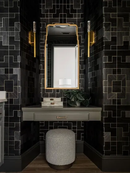 The Fretwork collection creates a sophisticated vanity nook within this powder room. The dark, geometric pattern provides a powerful backdrop for the gold-framed mirror and elegant seating.
