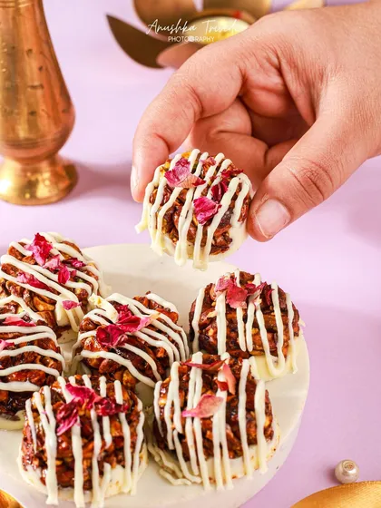 Mini desserts with white chocolate and rose petals. The hand reaching in adds a dynamic element, while the purple background gives it a modern festive look.